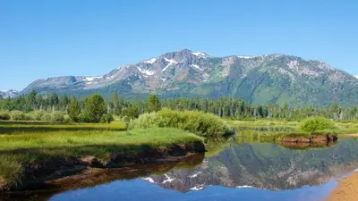 a mountain reflection in a lake with a mountain in the background at Tahoe Woods Heavenly - Walk to beach & Gondola to Heavenly Ski in South Lake Tahoe