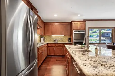 a kitchen with wooden cabinets and a stainless steel refrigerator at Tahoe Woods Villa - Walk to Beach and Gondola - Heavenly Ski in South Lake Tahoe