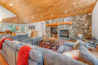 a living room with couches and a stone fireplace at The Lodge on Oaxaco - Epic Man Cave with Billiard Room in South Lake Tahoe