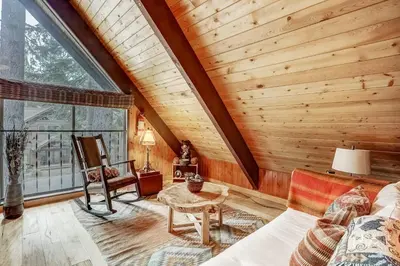 a living room with wooden walls and a large window at Woodland Escape - Cute Little Cabin in the Woods in South Lake Tahoe