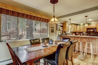 a kitchen and dining room with a wooden table and chairs at Woodland Escape - Cute Little Cabin in the Woods in South Lake Tahoe