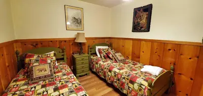 two beds in a room with wood paneling at Zephyr Cove Cabin - Walk to Lake & Beach in Zephyr Cove