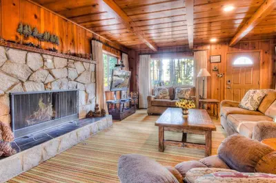 a living room with a large stone fireplace at Zephyr Cove Cabin - Walk to Lake & Beach in Zephyr Cove