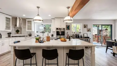 a kitchen with white cabinets and a large island with bar stools at Geraldine Drive by AvantStay Hot Tub Views Walk to Trails Game Room in Incline Village
