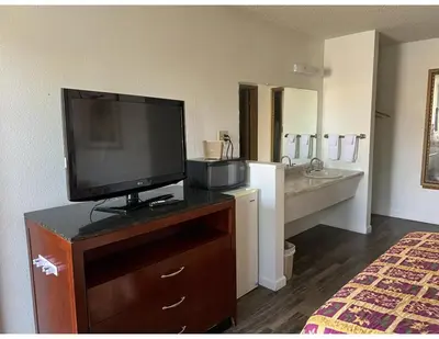 a hotel room with a television on a dresser with a bathroom at Oasis Inn and Suites in Fallon