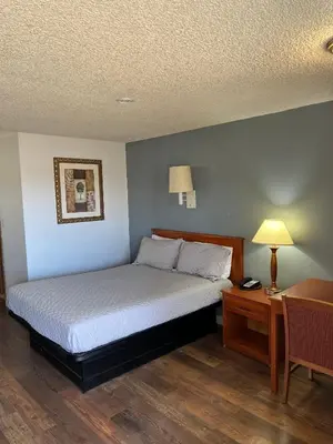 a bedroom with a bed and a table with a lamp at Oasis Inn and Suites in Fallon