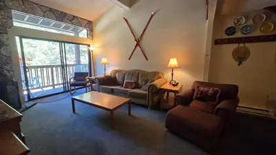 a living room with a couch and chairs and a clock at Eagle Summit Collection in Mammoth Lakes