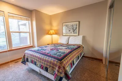 a bedroom with a bed and a lamp and two windows at RR-Hideaway_Down_Cyn 105 in June Lake