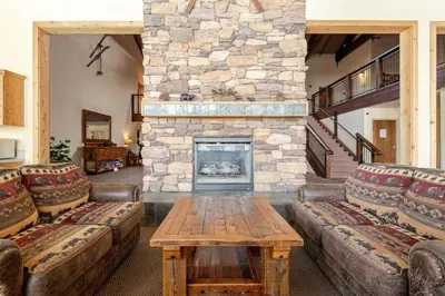 a living room with couches and a stone fireplace at The Lookout Loft Great views and King Sized Bed in Kirkwood