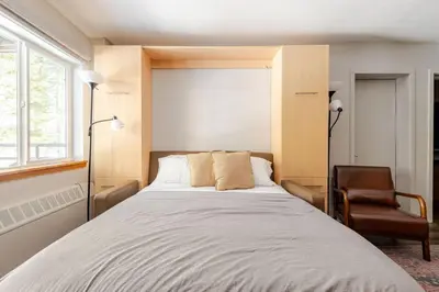 a bedroom with a large bed and a chair at Super-Efficient Studio with Full Kitchen Balcony & Smart Sleeping Options in Kirkwood