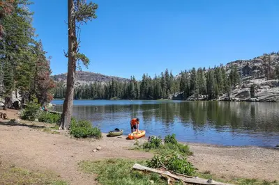 a man standing next to two canoes on a lake at Super-Efficient Studio with Full Kitchen Balcony & Smart Sleeping Options in Kirkwood