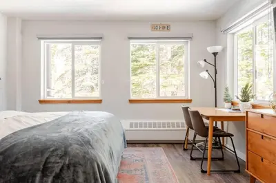 a bedroom with a bed and a desk and windows at Modern Kirkwood One Bedroom with Deck in Kirkwood