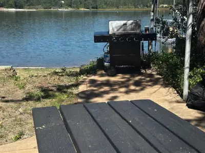 a grill sitting next to a body of water at Lewis Cabin - Boat Dock - Lake Front - Sleeps 10 in Bass Lake