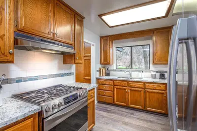 a kitchen with wooden cabinets and a stove top oven at Grand Riverside Retreat - Private Walkway to the River in Three Rivers