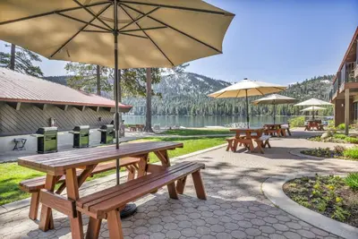 a group of picnic tables with umbrellas and a lake at 112 Bldg B condo in Truckee