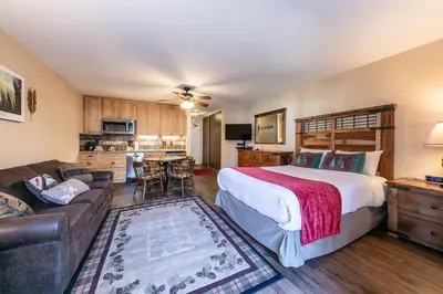 a bedroom with a bed and a couch and a kitchen at 215 Bldg B condo in Truckee