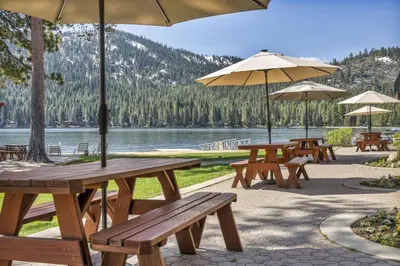 a group of picnic tables with umbrellas and a lake at 223 Bldg B condo in Truckee