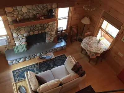 a living room with a couch and a stone fireplace at Apple Valley Cabin in Sonora
