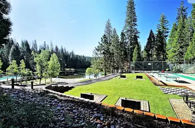 a large grassy field with a pool and trees at Cozy Cabin - Hot Tub, Fire Pit, & Pets in Arnold