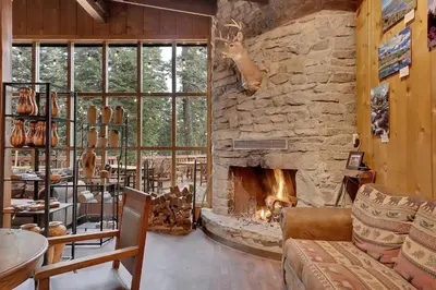a living room with a stone fireplace and a couch at Kit Carson Lodge in Kit Carson