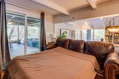 a living room with a leather couch and a large window at Kaweah River Cabin - Pool, Hot Tub, Movie Projector in Three Rivers