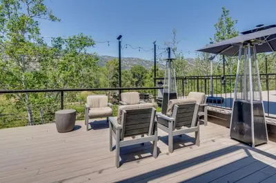a deck with chairs and an umbrella at Kaweah River Cabin - Pool, Hot Tub, Movie Projector in Three Rivers