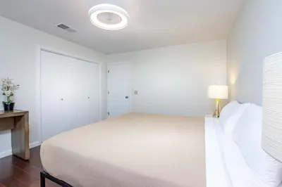 a white bedroom with a bed and a lamp at Serene Riverfront Home - 150 yds from the River in Three Rivers