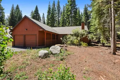 a red house with a garage in the woods at Serene Tahoe Donner Cabin mins to Lake, Ski, Golf in Truckee