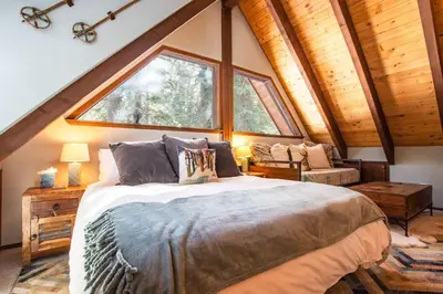 a bedroom with a bed and a large window at A-Frame Cabin - Hot Tub , BBQ , Family Fun in Tahoe Vista