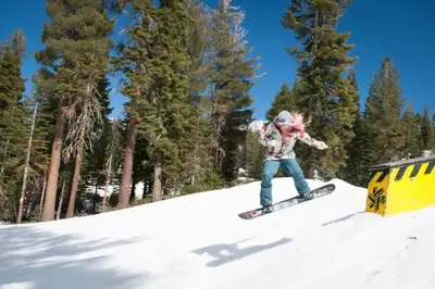 a person riding a snowboard down a snow covered slope at Charming Kings Beach Cabin, Hot Tub, Walk to Lake in Kings Beach