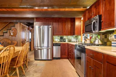 a kitchen with wooden cabinets and a stainless steel refrigerator at Walk to Lake West Shore Cabin Hot Tub DogOK EVplug in Homewood