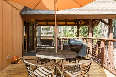 an umbrella on a deck with a table and chairs at Walk to Lake West Shore Cabin Hot Tub DogOK EVplug in Homewood