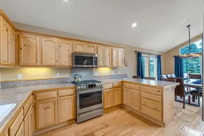 a large kitchen with wooden cabinets and a dining room at Chestnut Haus at Tahoe Donner By Tahoe Getaways - 4 BR w HOA Amenities in Truckee