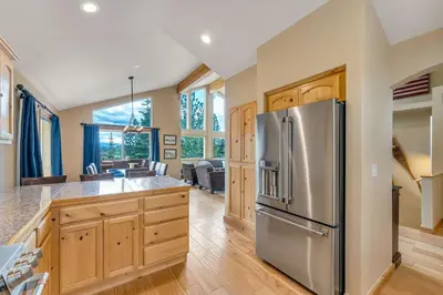 a kitchen with a stainless steel refrigerator and wooden cabinets at Chestnut Haus at Tahoe Donner By Tahoe Getaways - 4 BR w HOA Amenities in Truckee