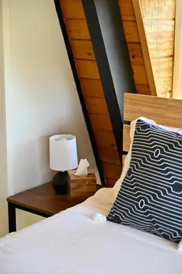 a bedroom with a bed and a table with a lamp at Modern A Frame,20min Yosemite,Sunset View, PetOkay in Oakhurst