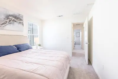a white bedroom with a large bed and a hallway at Spacious 4BR-3BA Cozy and Modern in Elk Grove in Elk Grove