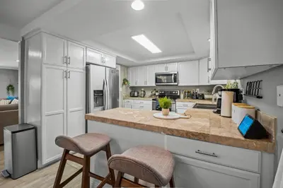 a kitchen with white cabinets and a counter with stools at MtnCity Views 4BR Firepit FamilyRetreat NearUNR in Reno