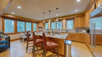 a kitchen with a large island with leather chairs at Cedars at Palisades by AvantStay Hot Tub Resort Access and Mountain Views in Olympic Valley