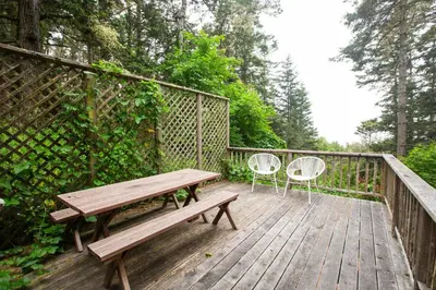 a wooden deck with a bench and two chairs at Redwoods Oceanview Retreat