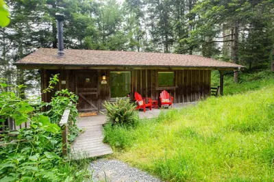 a cabin in the woods with red chairs and a porch at Redwoods Oceanview Retreat