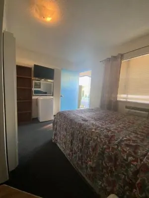 a hotel room with a bed and a kitchen at Hotel Paisano in Reedley