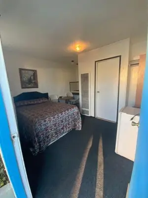 a bedroom with a bed and a room with a door at Hotel Paisano in Reedley