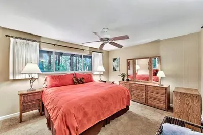 a large bedroom with a red bed and a mirror at 1510 Wildwood, Sitzmark 4 home in South Lake Tahoe
