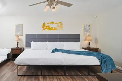 a bedroom with a large bed with a blue blanket on it at Scenic Mountain Views w Heated Pool, Game Room, and Hottubs in Oakhurst