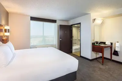 a bedroom with a white bed and a bathroom with a sink at Hyatt Place Sacramento Roseville in Roseville