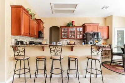 a kitchen with wooden cabinets and bar stools at Rose Garden in Sacramento