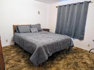 a bedroom with a bed with a gray comforter and a window at Meadow View Cabin in Wilsonia in Wilsonia