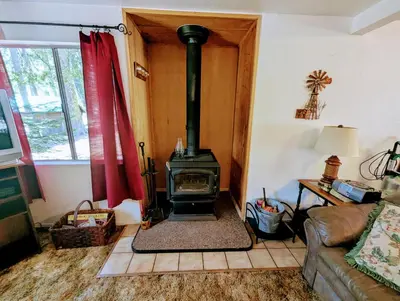 a living room with a wood stove in the corner at Meadow View Cabin in Wilsonia in Wilsonia