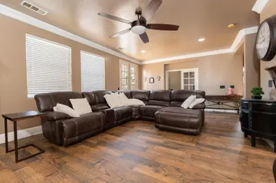 a living room with a leather couch and a ceiling fan at Private room--Ideal for working professionals-- in Tulare