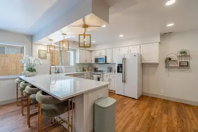 a kitchen with white cabinets and a white refrigerator at The Deco Retreat - UNR - Pet Friendly in Reno